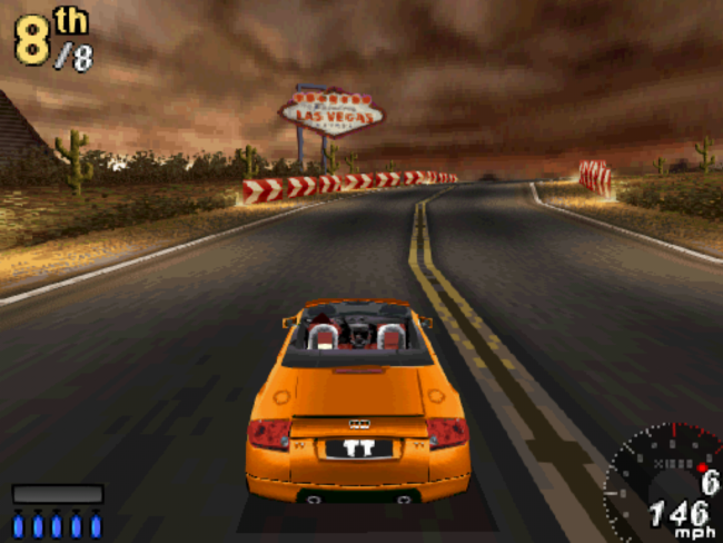 An orange sports car drives toward the Welcome to Last Vegas sign.